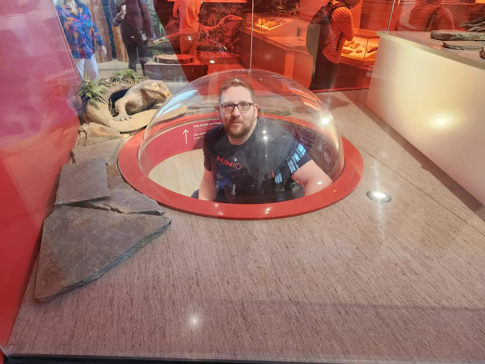 Mark peeking out of a bubble dome inside a fossil exhibit